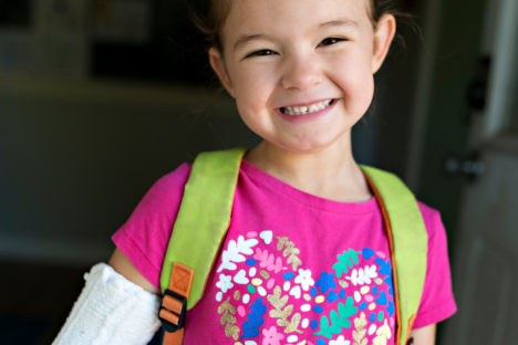 child smiling with an arm cast